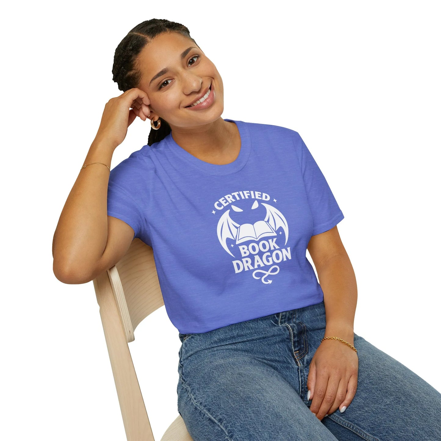 Woman wearing a relaxed fit Certified Book Dragon T-Shirt, cozy at home with her cat and books, a perfect gift for book lovers.