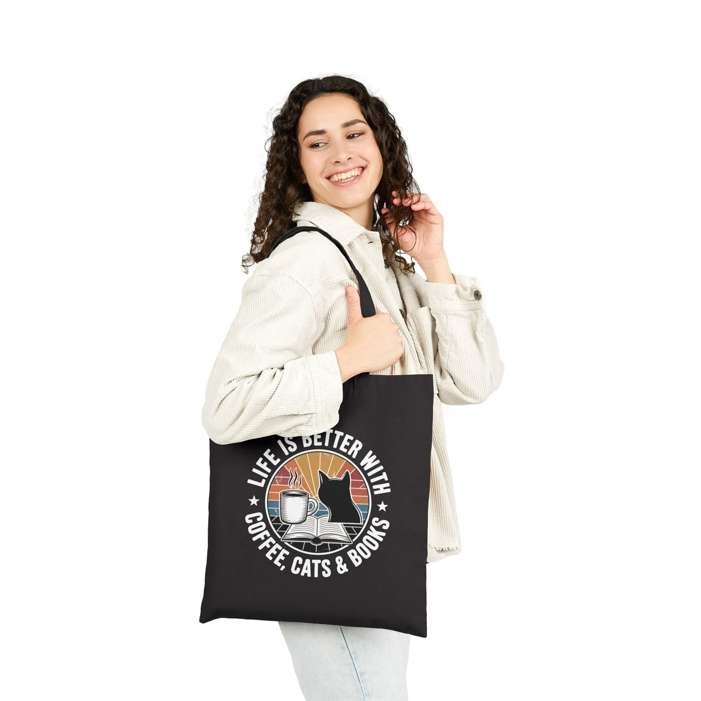 A person holding the Sunset Reads & Whiskers Tote Bag featuring a warm retro design with text: 'Life is better with coffee, cats & books'.
