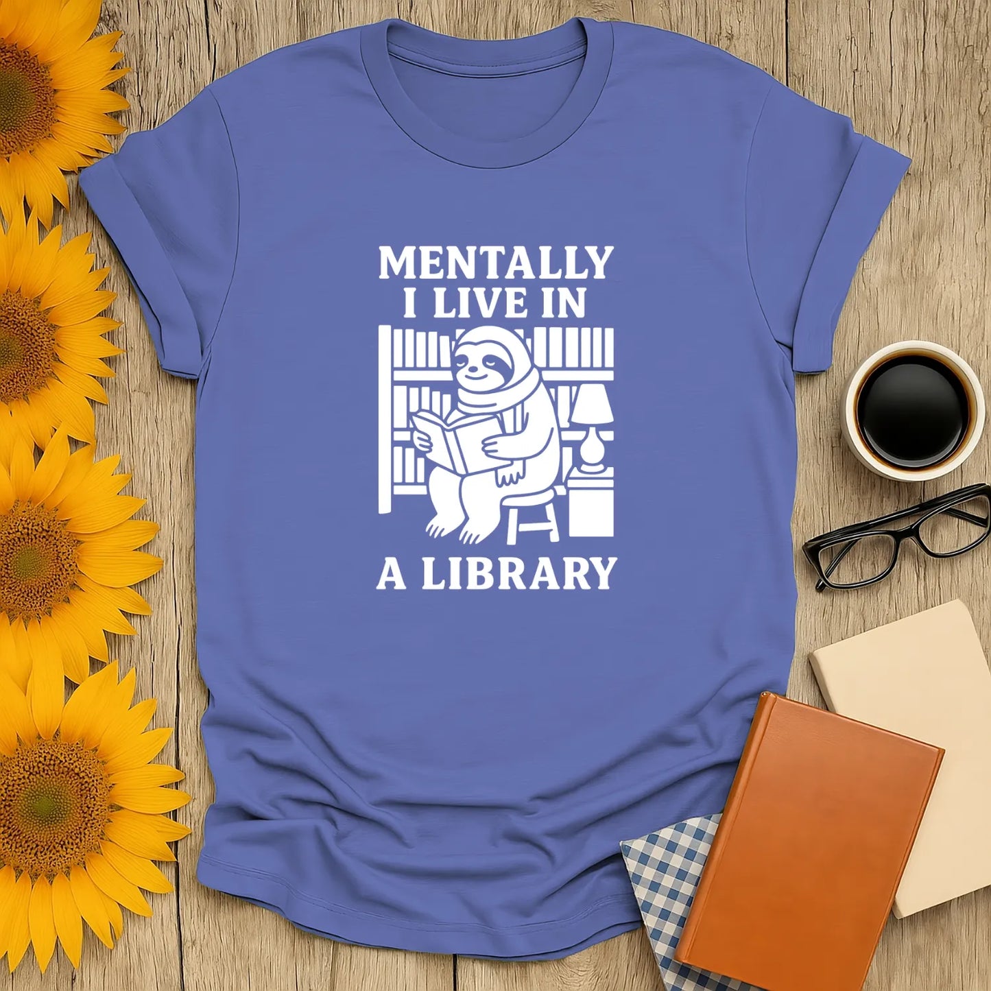 Light blue t-shirt featuring a sloth reading in a library with the text 'Mentally I Live In A Library'—perfect for book lovers!
