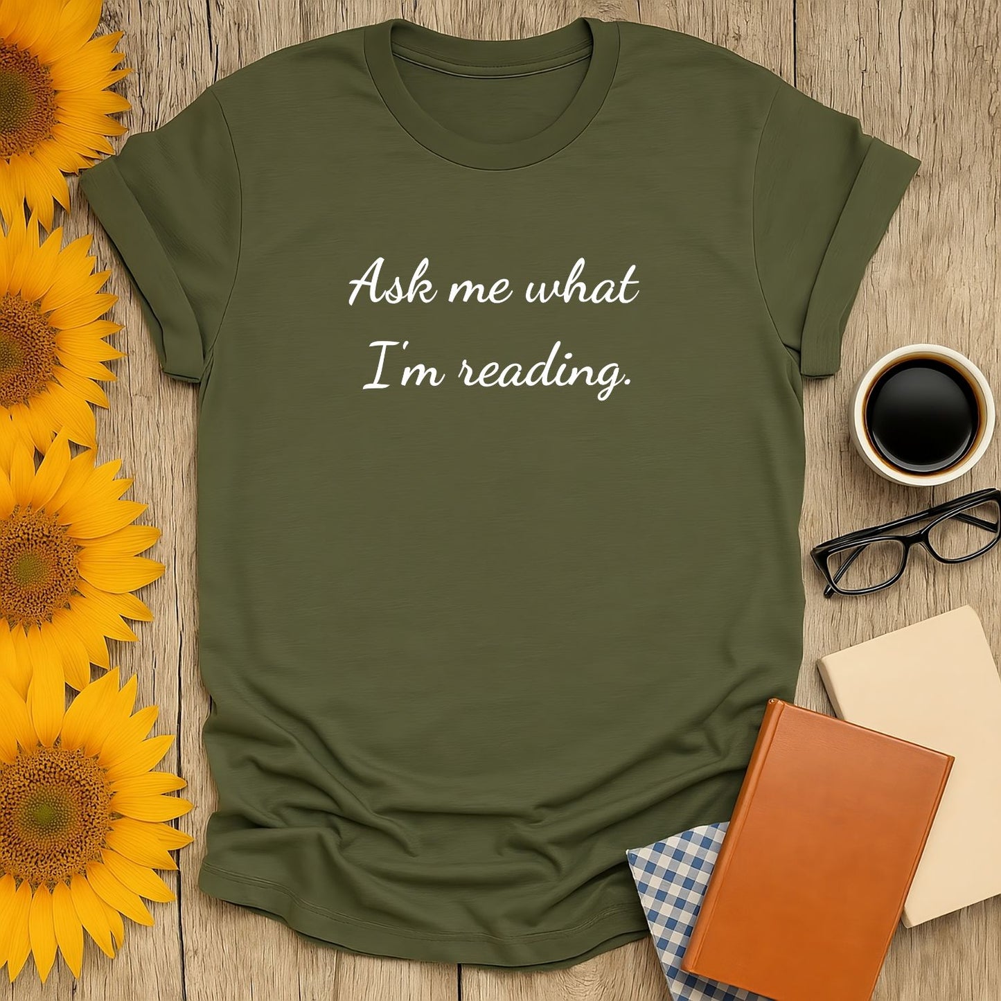 Unisex Ask Me T-Shirt, perfect for book lovers, featuring soft print, breathable cotton, surrounded by sunflowers and reading accessories.
