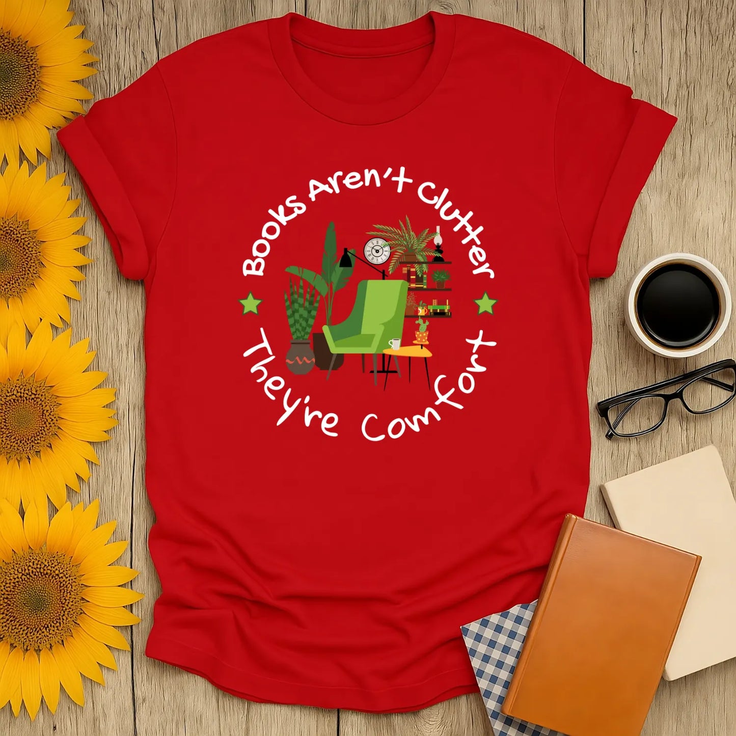 Funny reading tee featuring a cozy chair, books, and greenery with the text 'Books Aren't clutter, They're Comfort.' Perfect gift for book lovers!