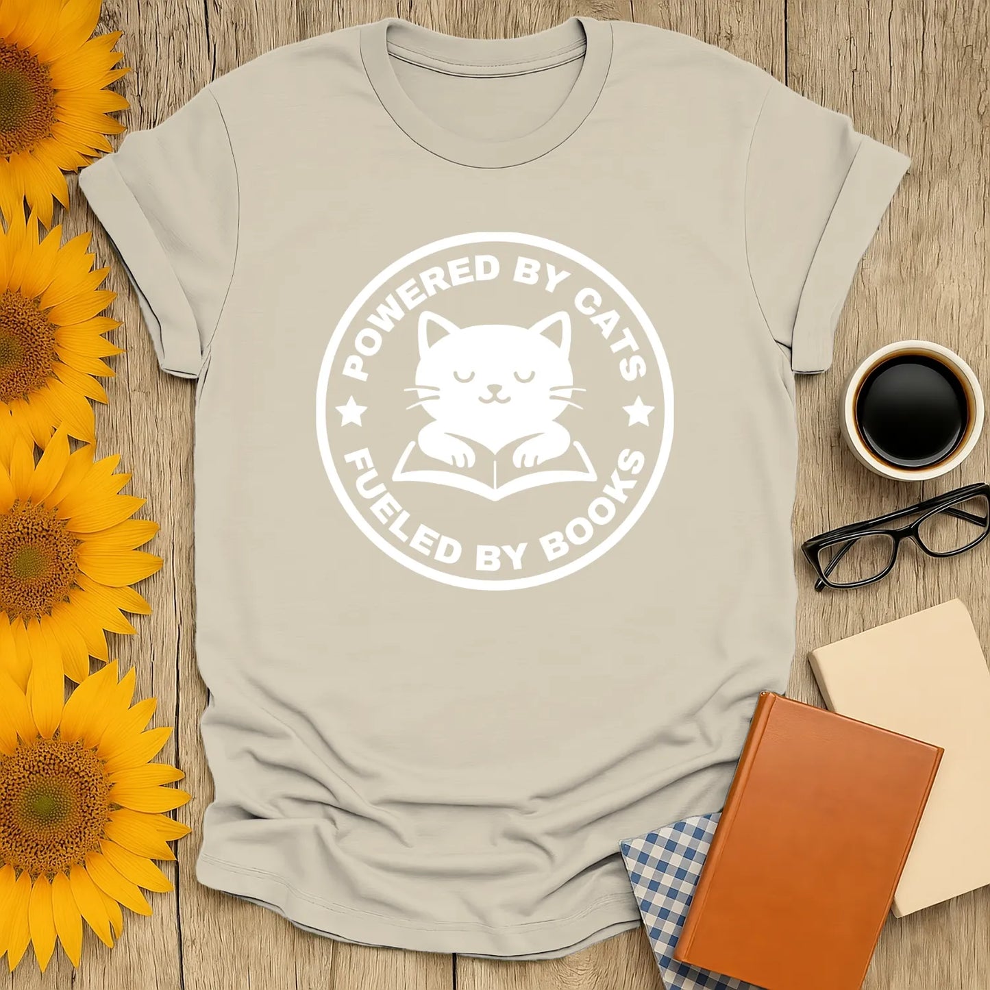 Funny reading tee featuring a cute cat illustration with text 'Powered by Cats, Fueled by Books', perfect for book lovers.