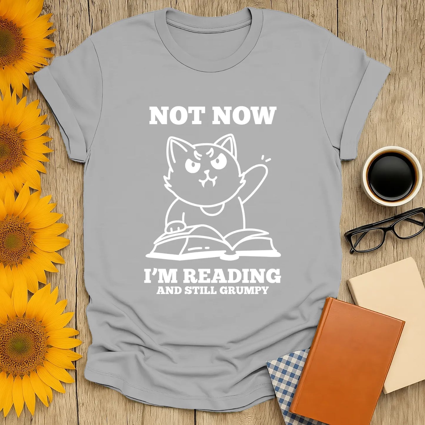 Funny cat illustration on a tee with text "Not Now I'm Reading and Still Grumpy" perfect for book lovers and cozy reading vibes.