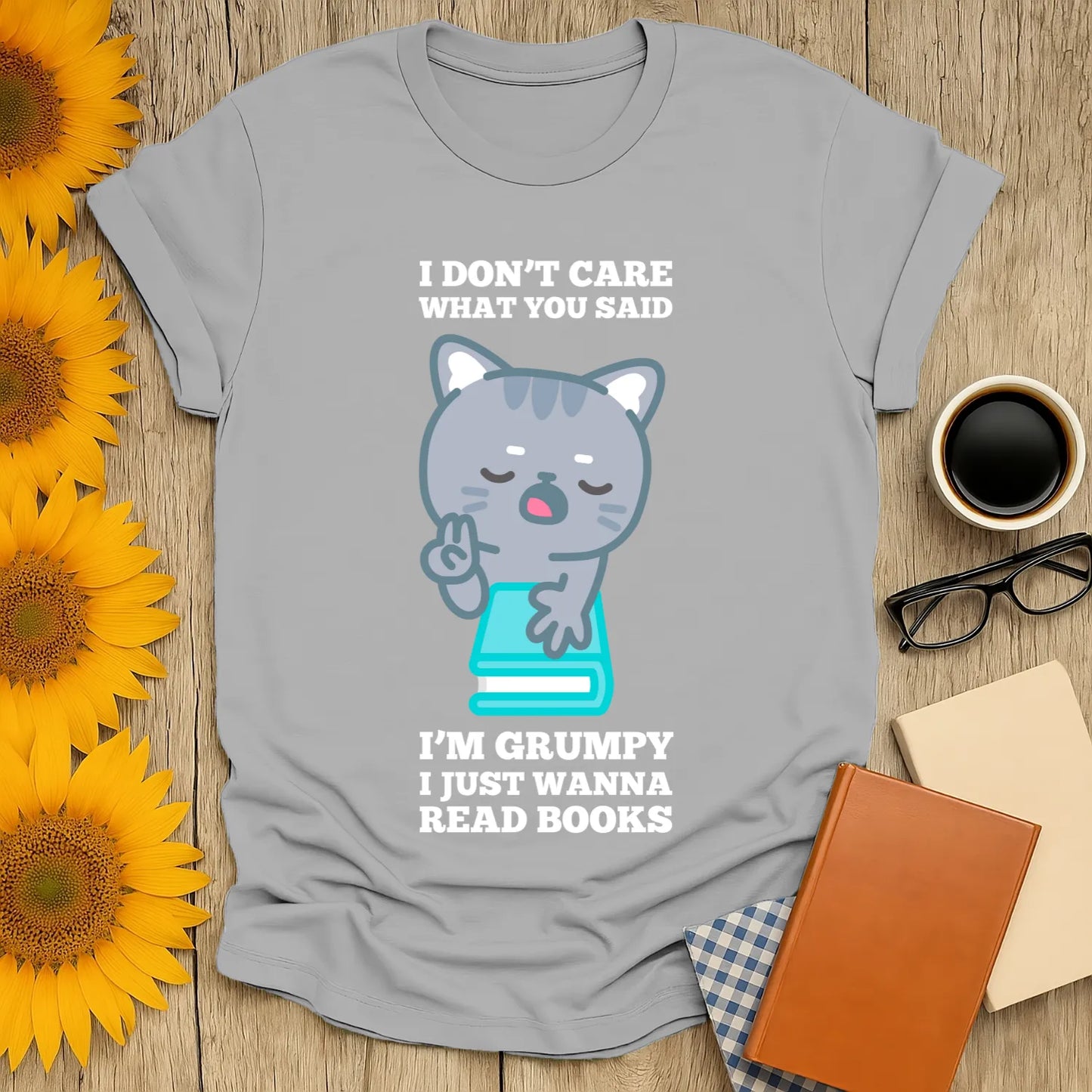 Gray t-shirt featuring a grumpy cat holding a book with text: "I don't care what you said, I'm grumpy I just wanna read books." Perfect for book lovers!