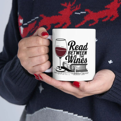 A woman holds a mug featuring a wine glass and the text 'Read Between the Wines', perfect for book lovers.