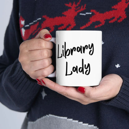 Cozy Library Lady Mug held by a reader, showcasing bold text for book lovers, perfect for coffee or tea.