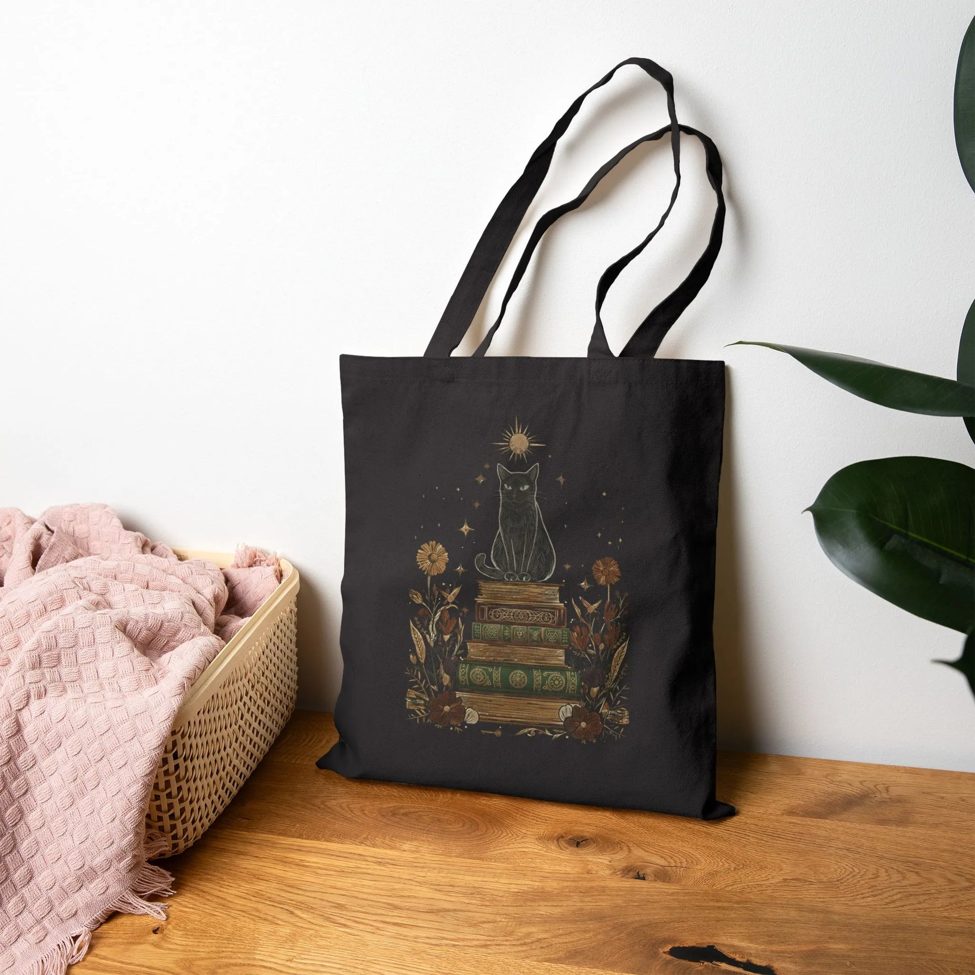 Mystic Cat & Books Tote Bag showcasing a black cat atop vintage books with floral accents, perfect for book lovers and cat fans.
