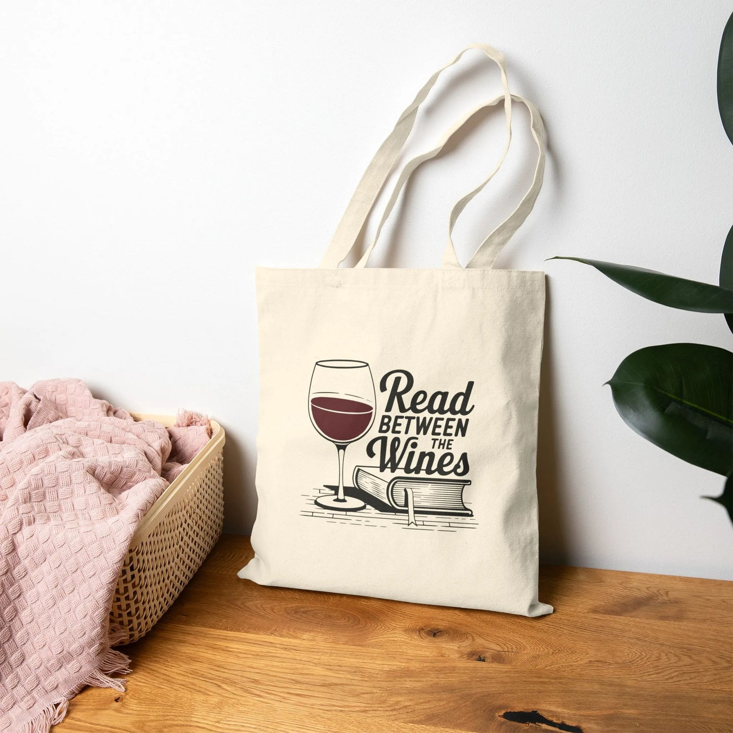 Read Between the Wines Tote Bag featuring a wine glass and book illustration, perfect for book lovers enjoying wine.