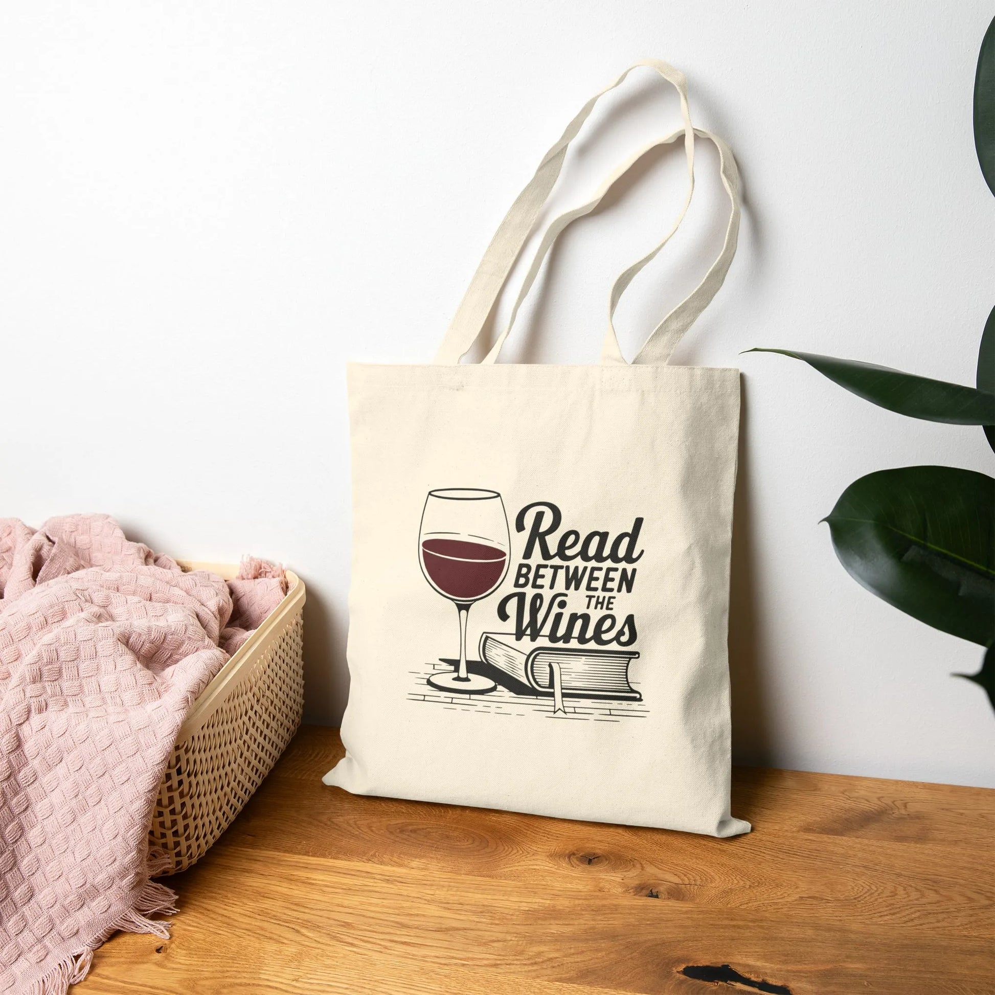 Read Between the Wines Tote Bag featuring a wine glass and book illustration, perfect for book lovers enjoying wine.