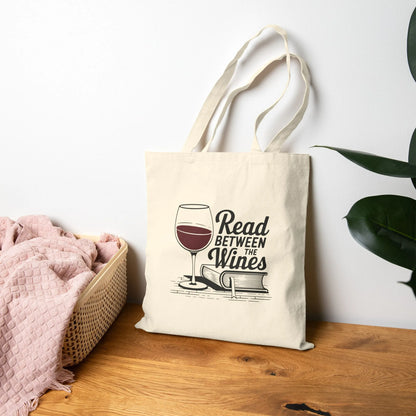 Read Between the Wines Tote Bag featuring a wine glass and book illustration, perfect for book lovers enjoying wine.