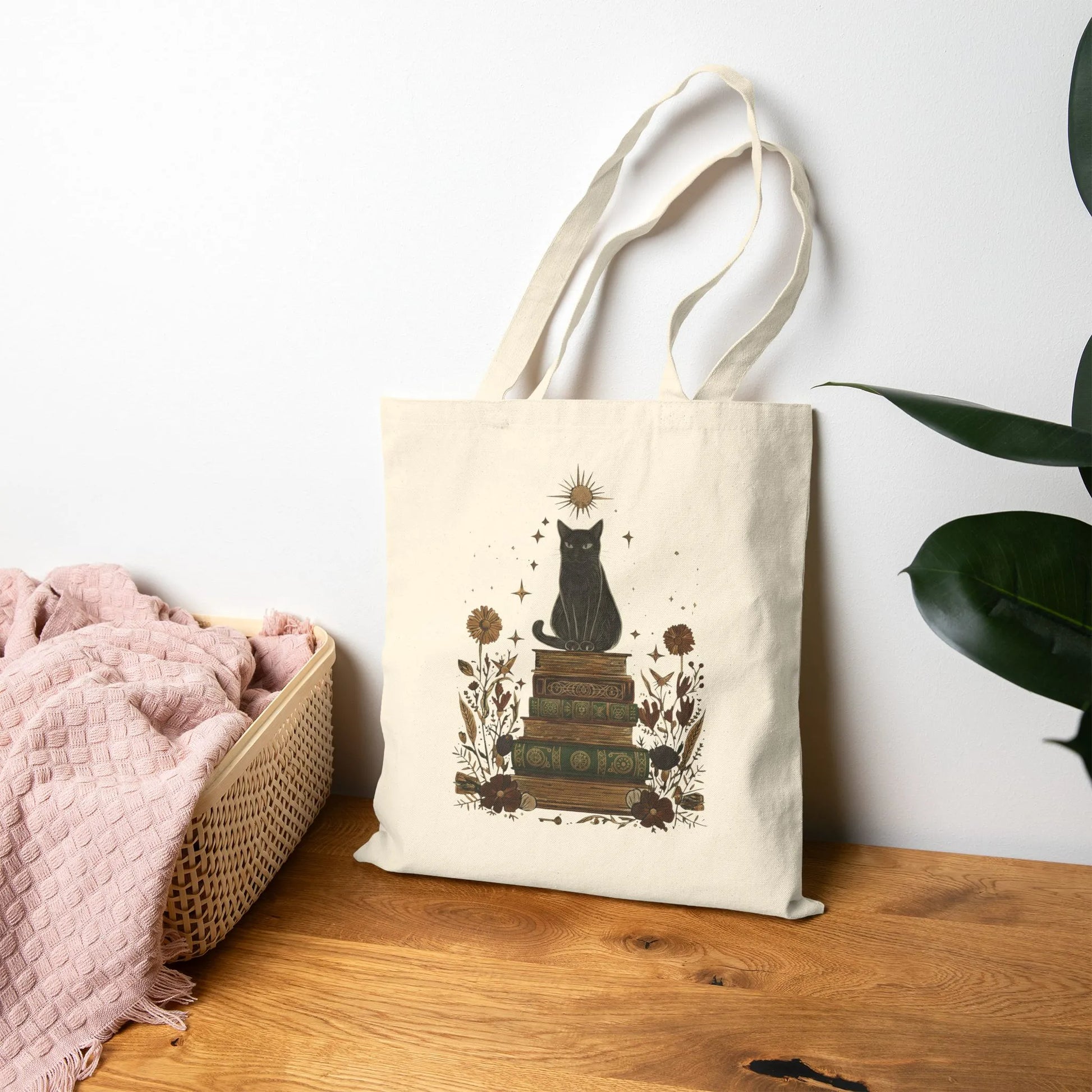 Mystic Cat & Books Tote Bag featuring a black cat atop vintage books and floral accents, perfect for book lovers and cat enthusiasts.
