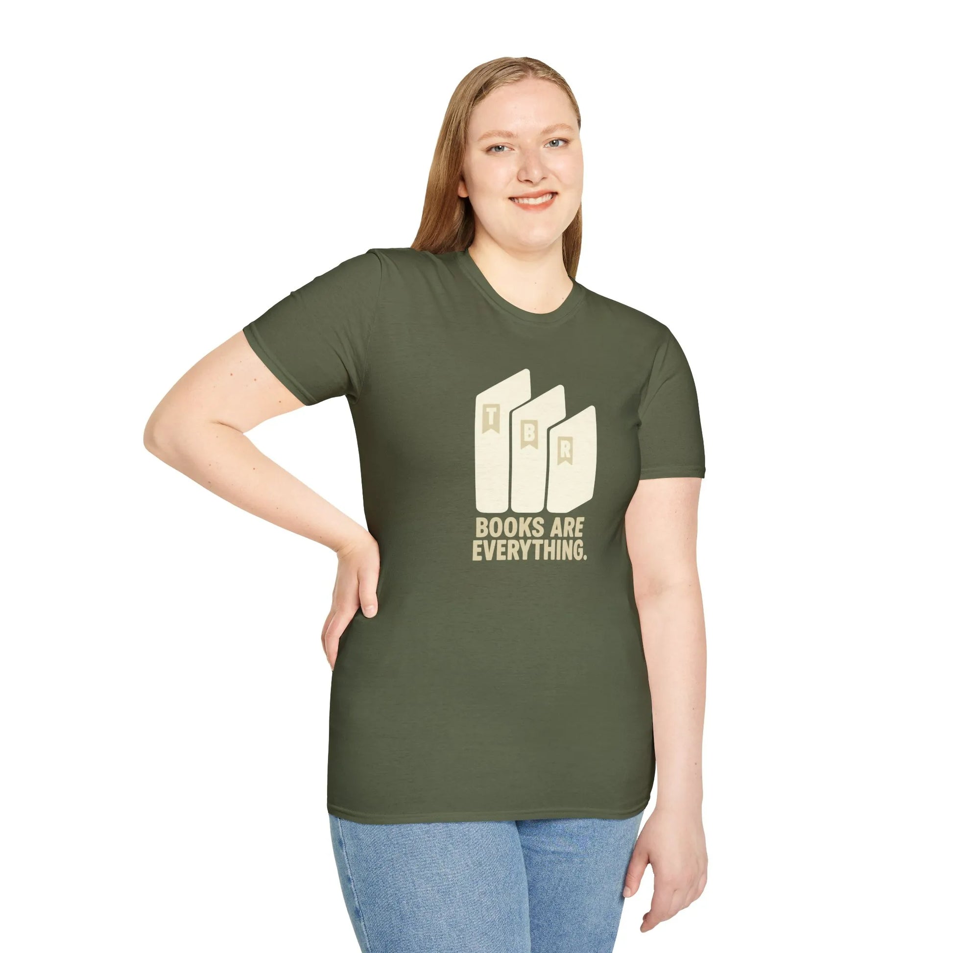 Cozy living room scene with a book lover wearing a relaxed fit Books Are Everything T-Shirt, surrounded by books and a cat.