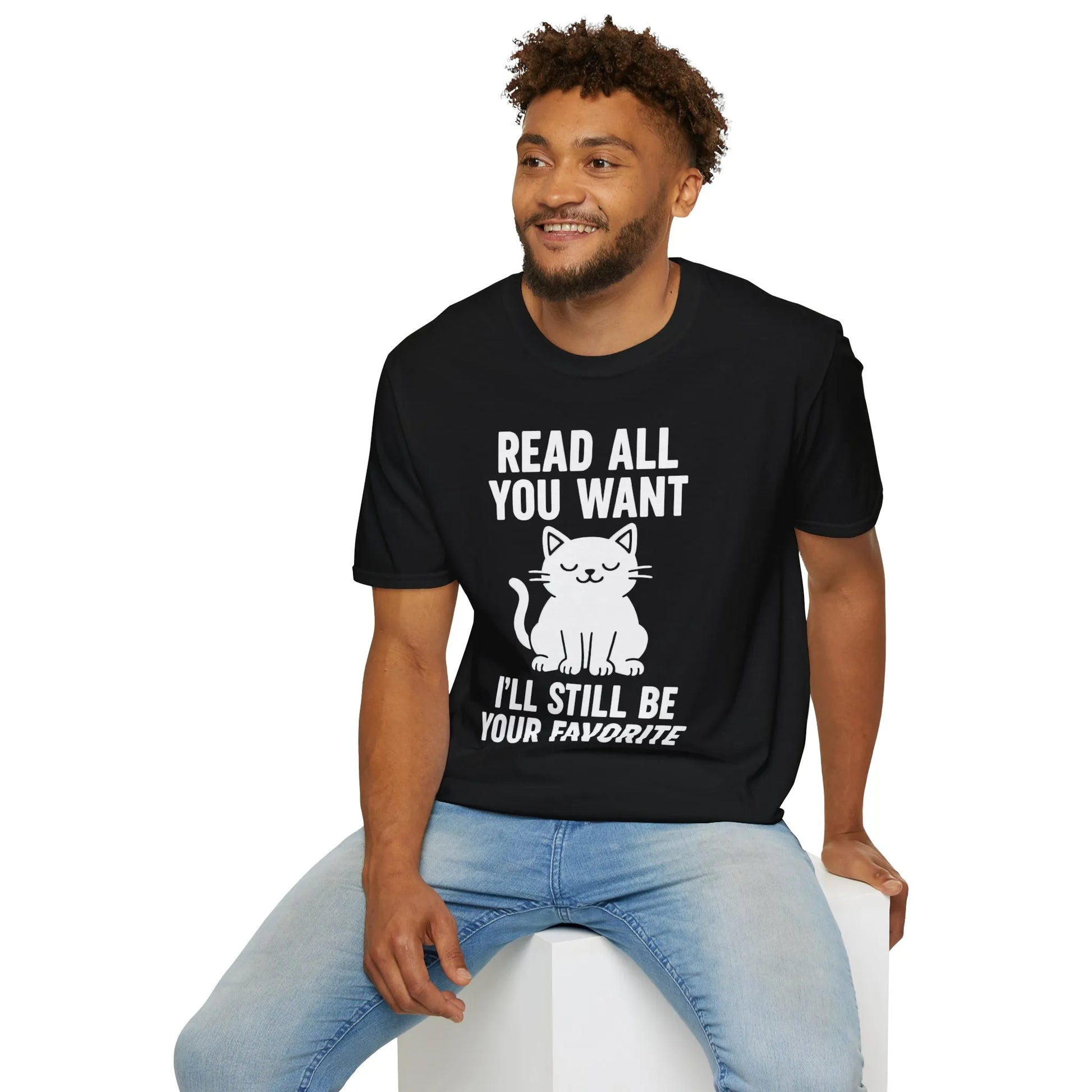 Cozy black t-shirt featuring a playful cat illustration and text: 'Read All You Want, I'll Still Be Your Favorite.' Perfect gift for book lovers.