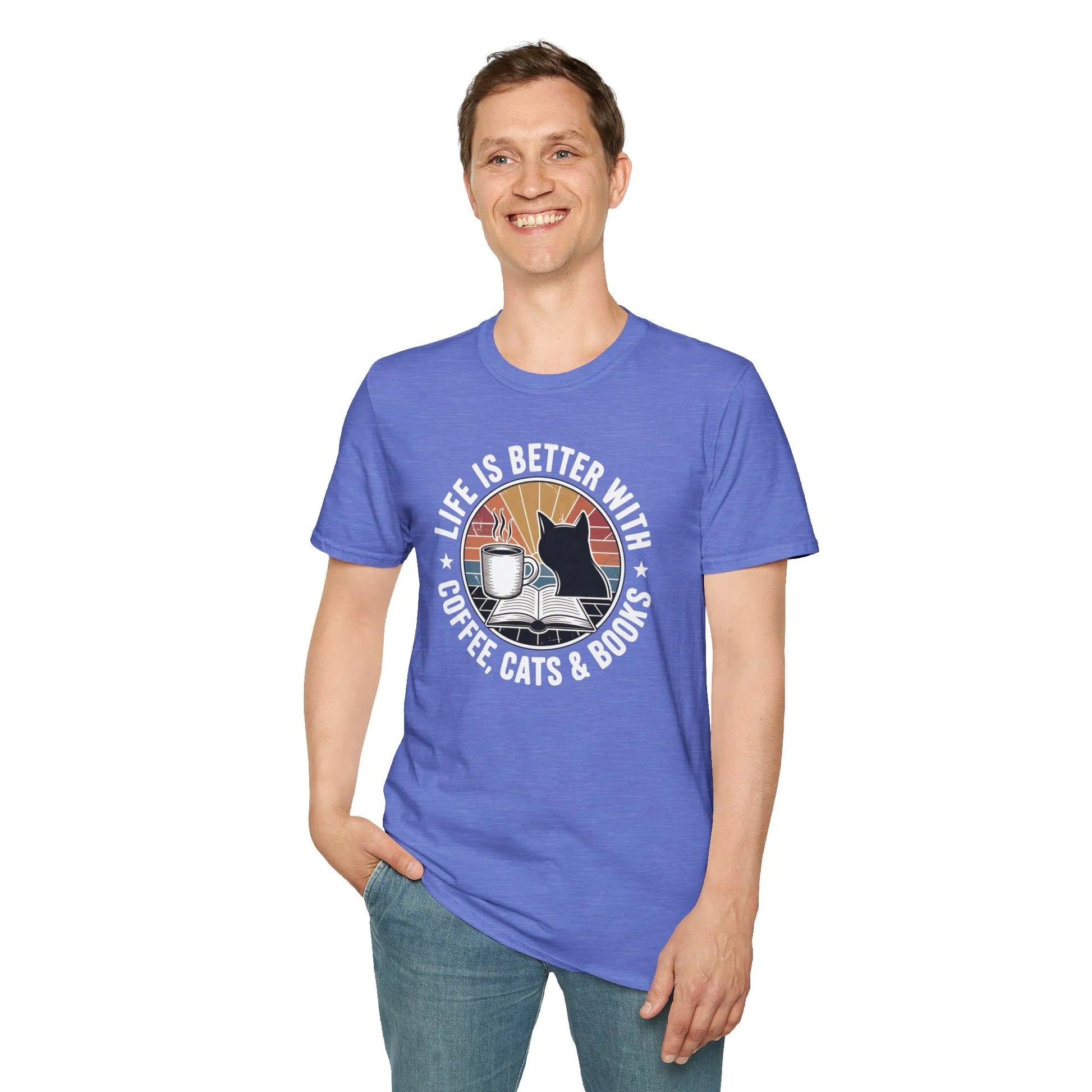 Man wearing a relaxed fit Sunset Reads & Whiskers T-Shirt, enjoying a cozy reading moment with a cat and coffee.