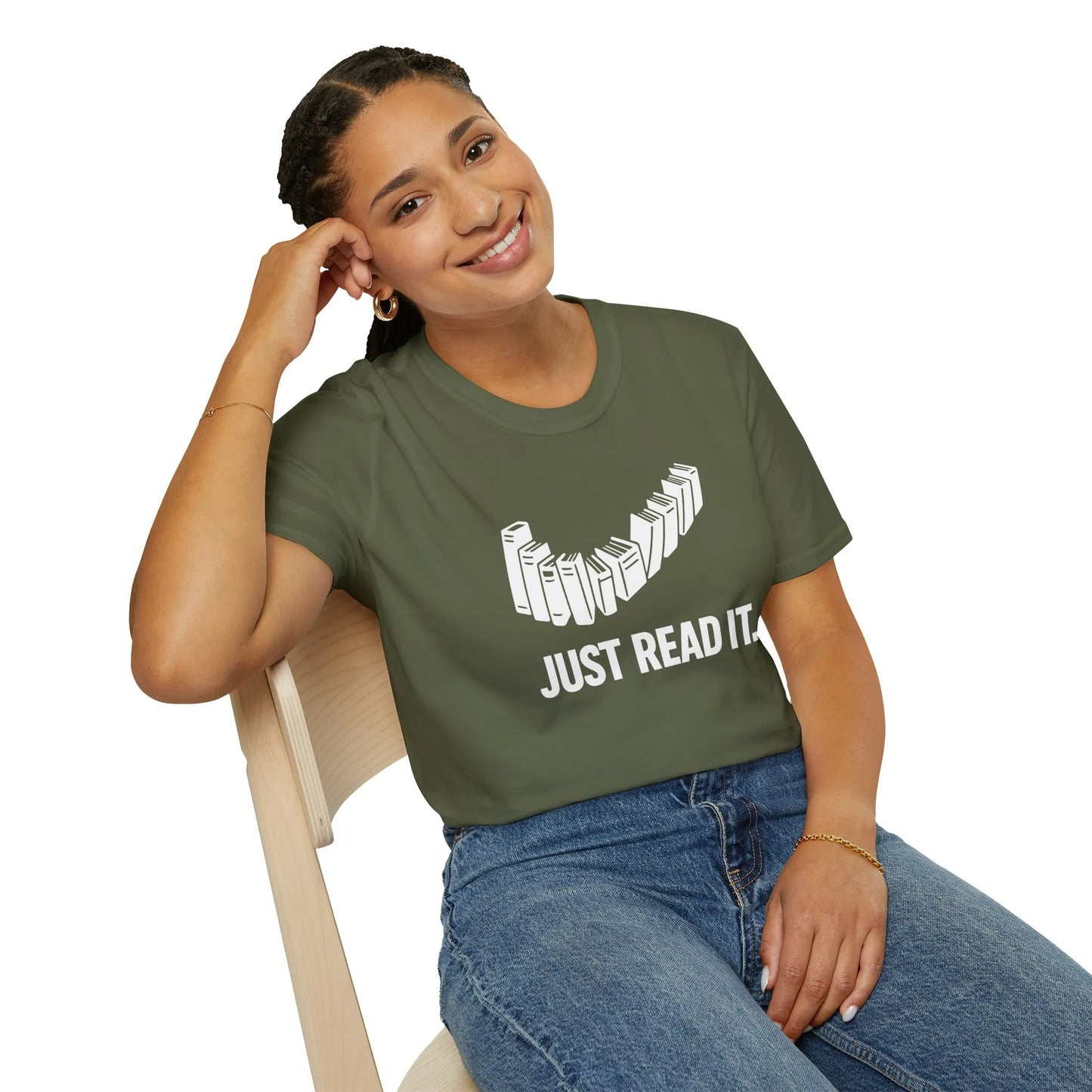 Smiling woman in a cozy setting wearing a relaxed Just Read It T-Shirt, surrounded by books; perfect for book lovers and reading lifestyle.