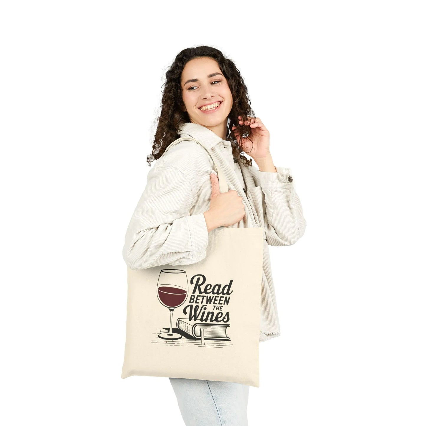 A joyful person holding the 'Read Between the Wines Tote Bag' featuring a wine glass and playful text, perfect for book lovers.