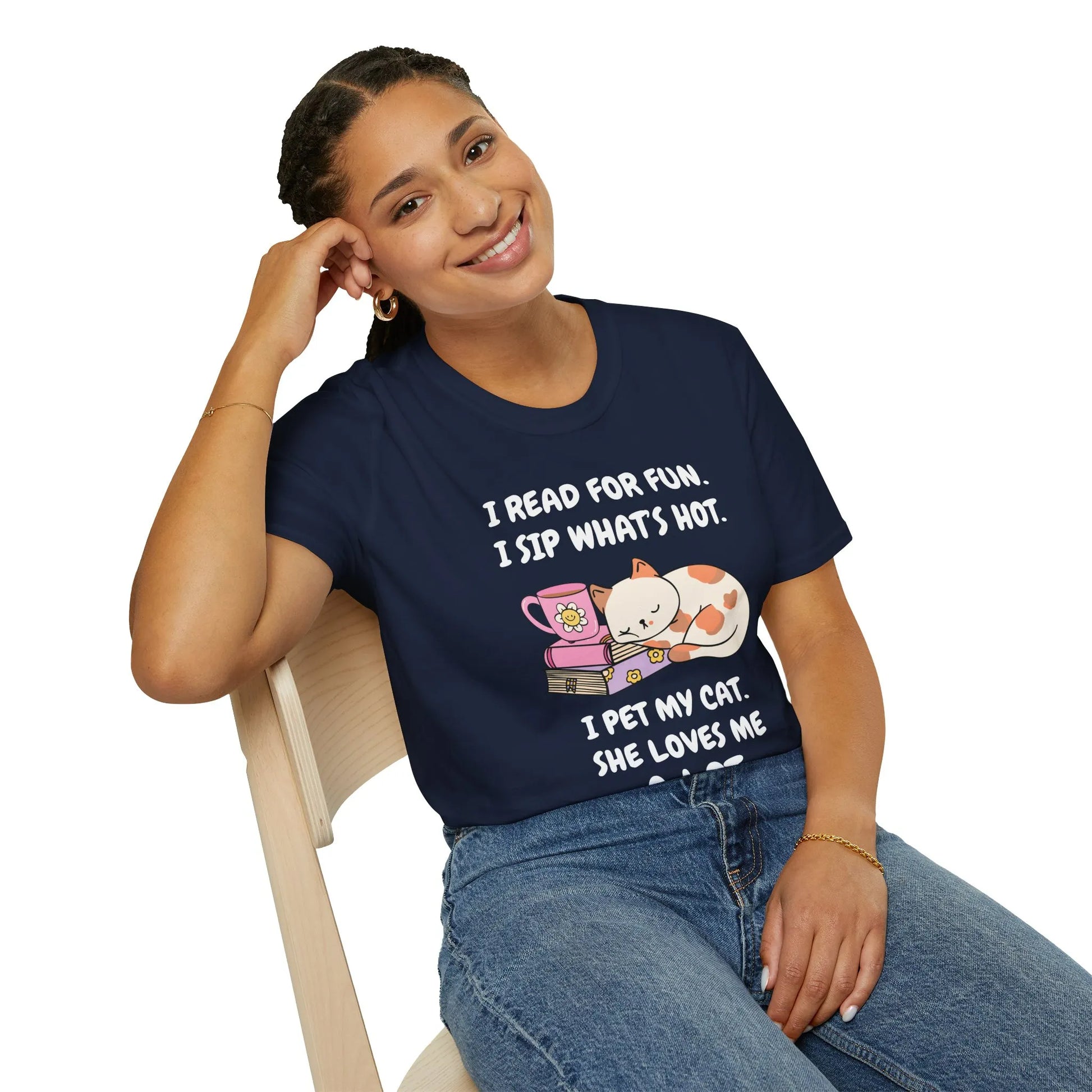Smiling woman wearing a navy shirt with cat illustrations and text about reading and sipping, perfect for book lovers.