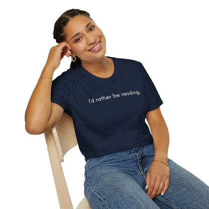 A relaxed fit 'Rather Be Reading T-Shirt' worn by a smiling woman, capturing a cozy reading lifestyle in a book nook.