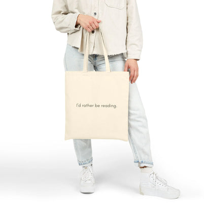 Minimalist Rather Be Reading Tote Bag held by a person, perfect for book lovers who prefer cozy reading moments.