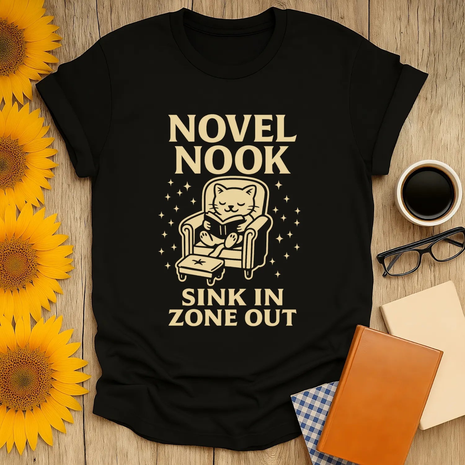 Cozy black Novel Nook t-shirt with a cat reading, perfect gift for book lovers who enjoy cats, coffee, or tea.