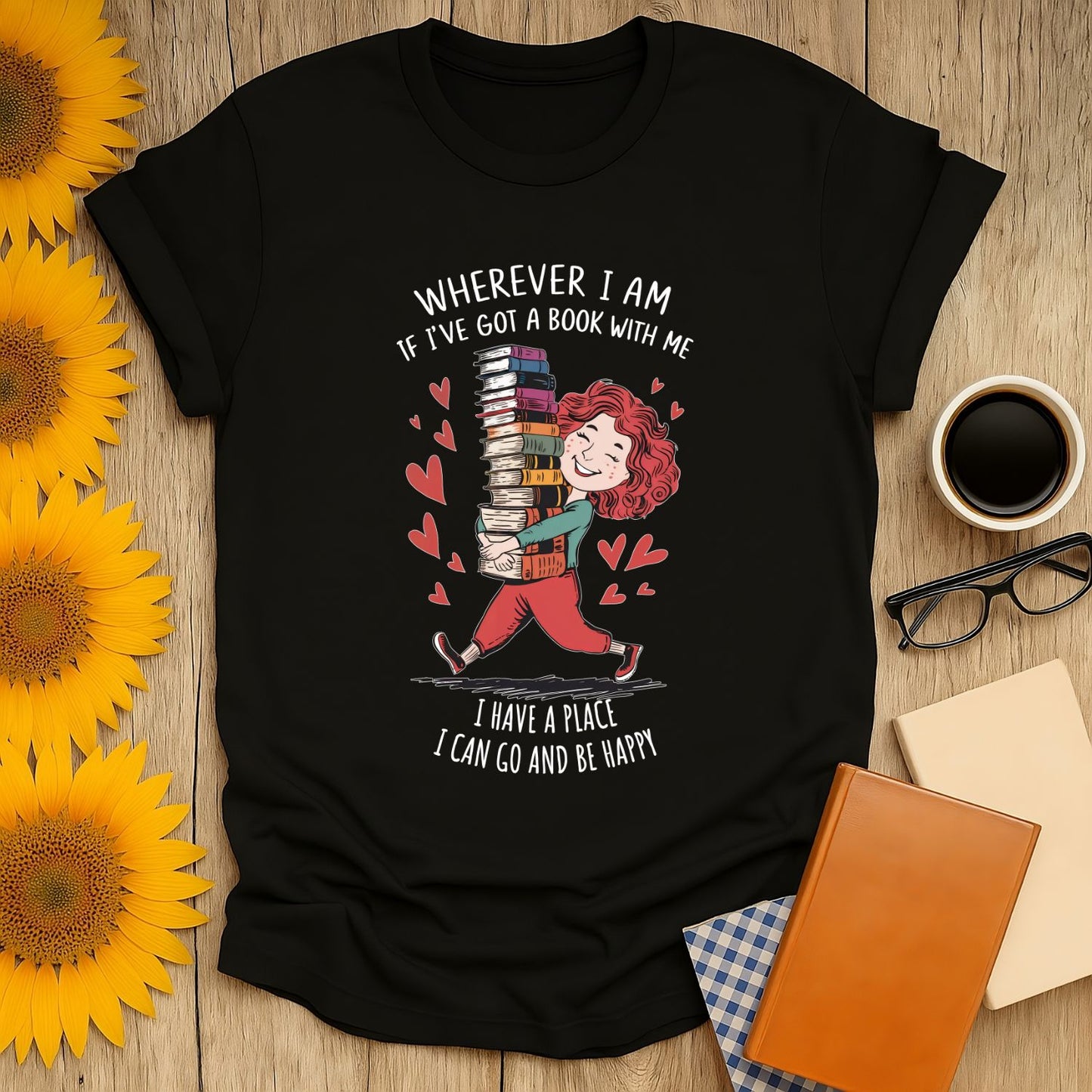 Book lover shirt with a cheerful reader carrying stacked books, surrounded by hearts; perfect for cozy moments with tea or coffee.