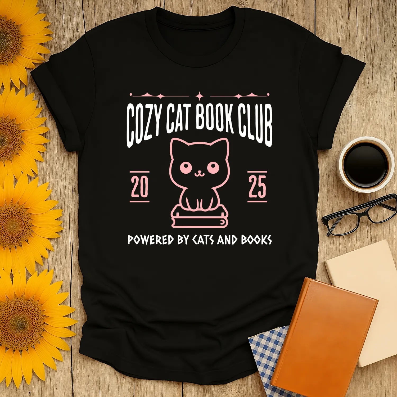 Cozy Cat Book Club T-Shirt showcases a cute cat with books, text reads "Powered by Cats and Books". Perfect gift for cozy readers!