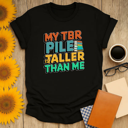 Black unisex T-shirt with 'My TBR Pile is Taller Than Me' text, perfect for book lovers who enjoy cozy reading vibes.