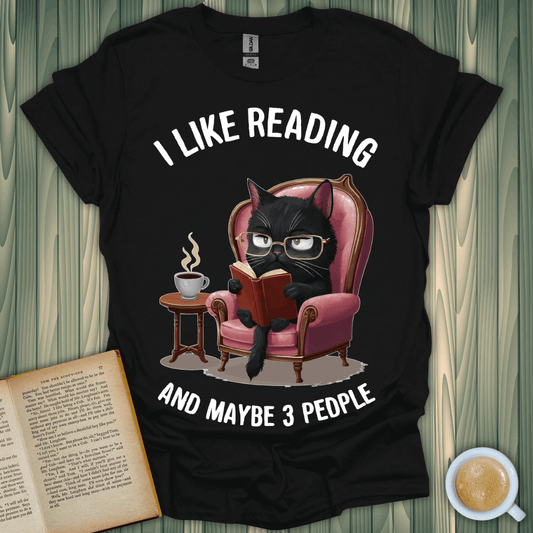 Black cat reading on a cozy chair t-shirt, perfect for book lovers who enjoy a few friends!