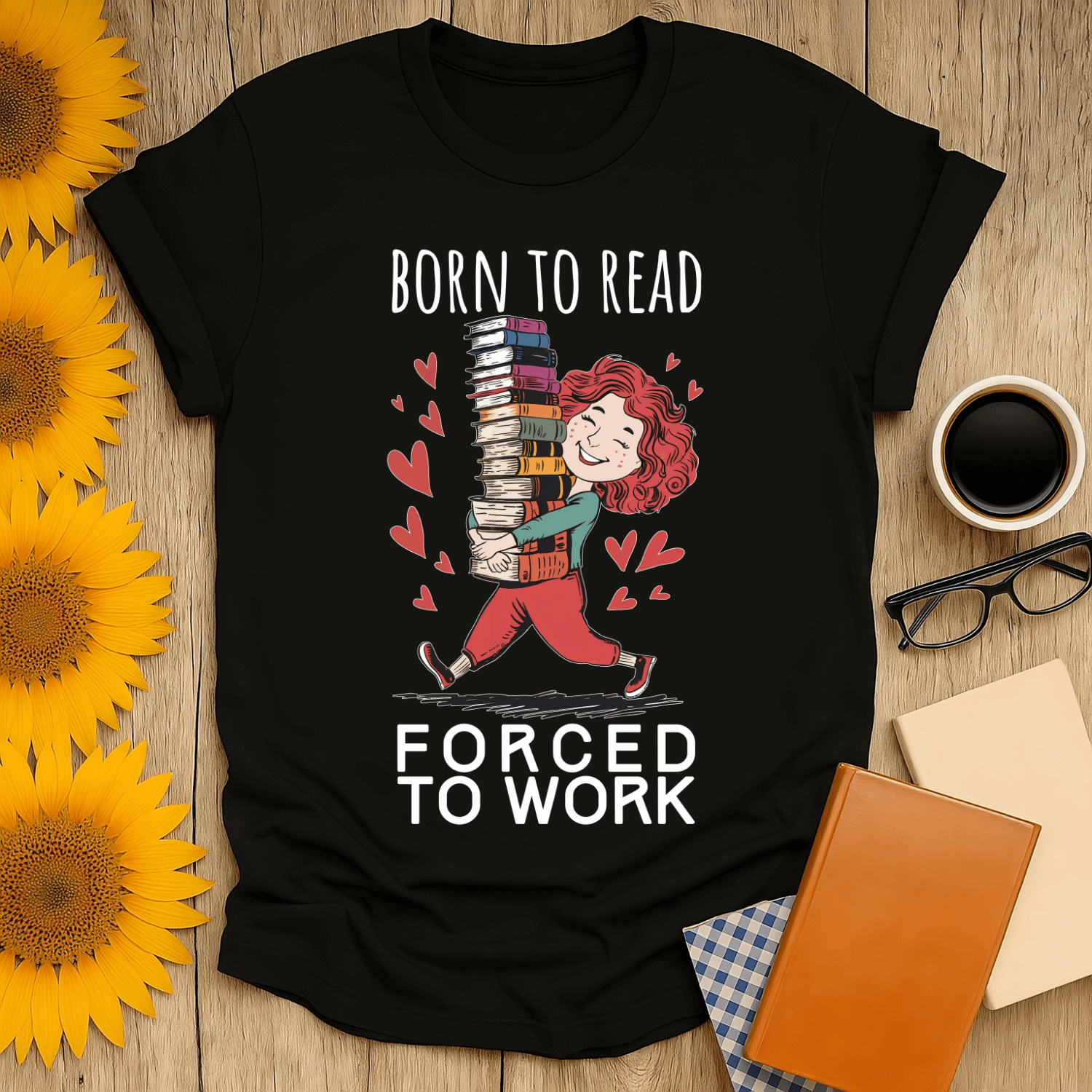 Black t-shirt with 'Born to Read, Forced to Work' design for book lovers, paired with coffee and accessories.