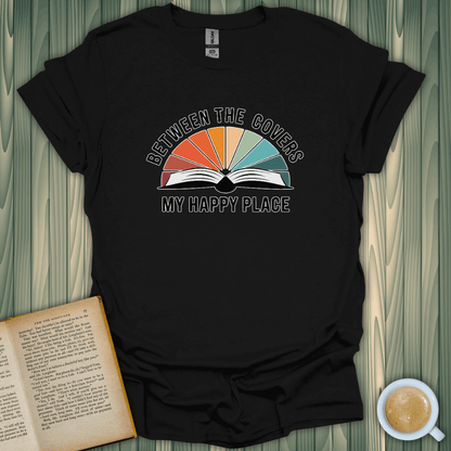 Unisex black t-shirt with rainbow design that reads 'Between the Covers My Happy Place' for book lovers.