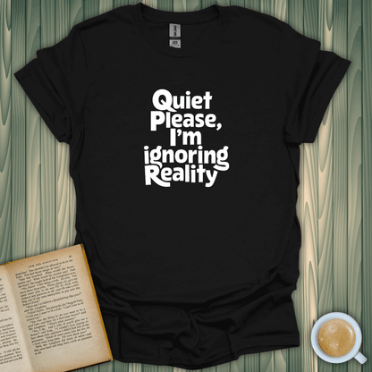 Black t-shirt with 'Quiet Please, I'm Ignoring Reality' text, perfect for book lovers seeking comfort.