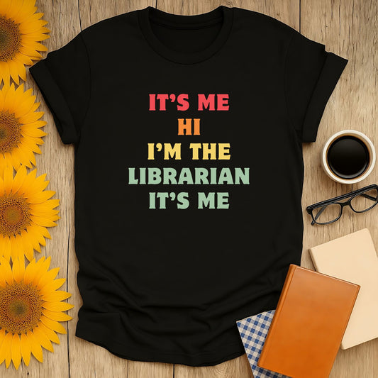 Black librarian t-shirt with colorful text: "It's me, Hi, I'm the Librarian, It's me," perfect for book lovers and gifts.