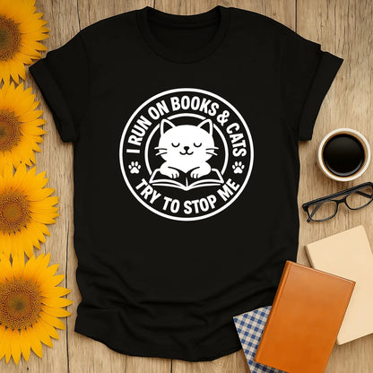 Cozy black cat reading shirt with text: 'I RUN ON BOOKS & CATS TRY TO STOP ME', perfect for book lovers and cat enthusiasts.