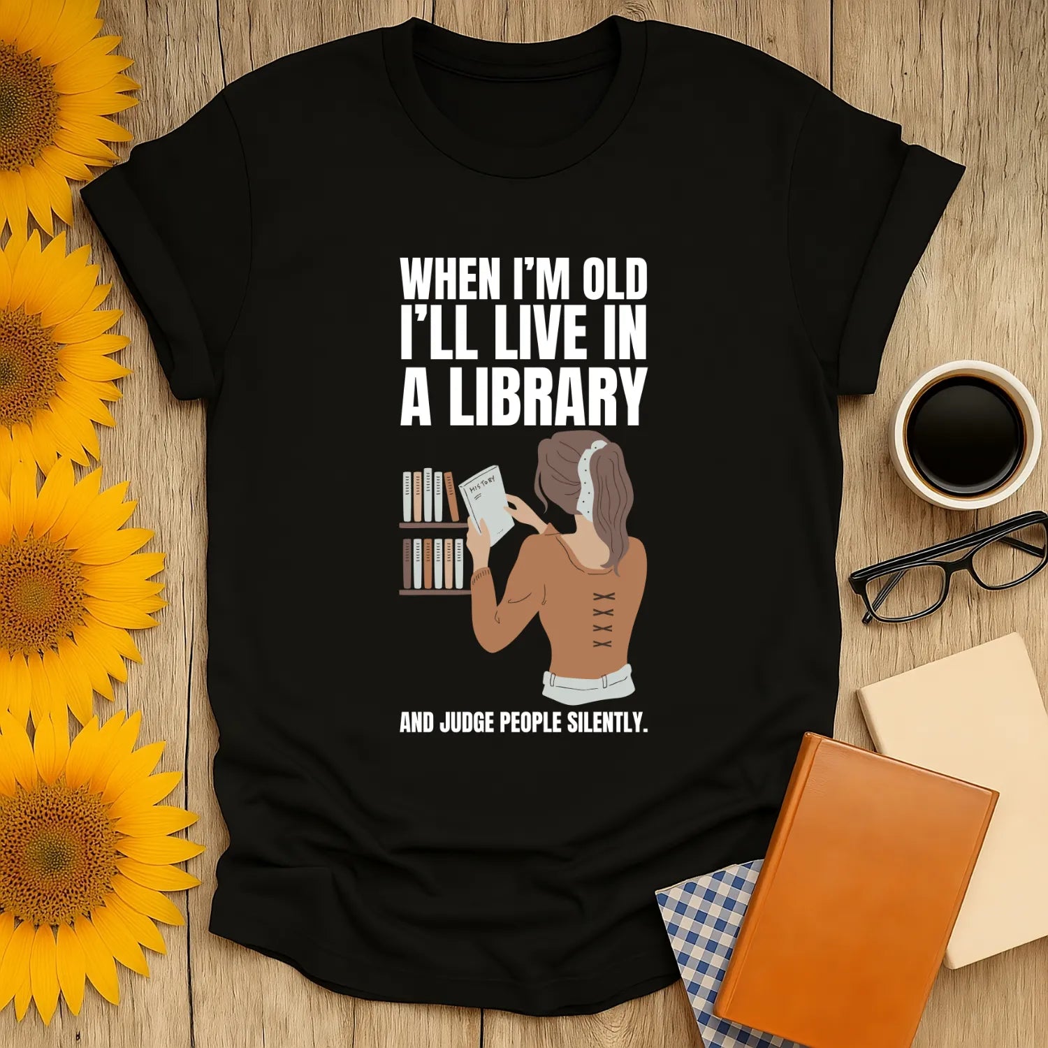Funny book lover shirt featuring a woman reading in a library with text: 'When I'm old I'll live in a library and judge people silently.'