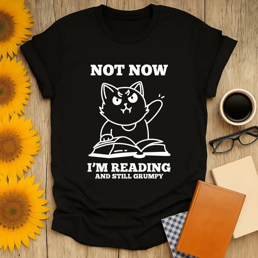 Funny cat shirt with text "Not Now I'm Reading and Still Grumpy"—perfect for book lovers who enjoy cozy reading days!