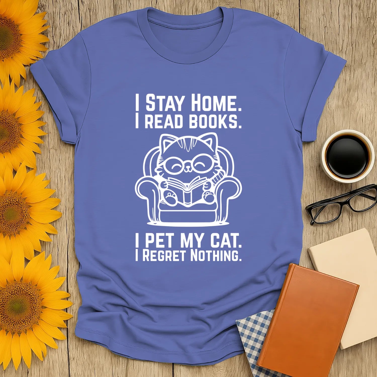 Cozy blue T-shirt featuring a cat reading, stating 'I stay home, I read books. I pet my cat. I regret nothing.' Perfect for book lovers!