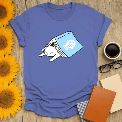Cozy cat tucked into a book on a blue shirt, perfect for book lovers and ideal gifts for readers who love coffee or tea.
