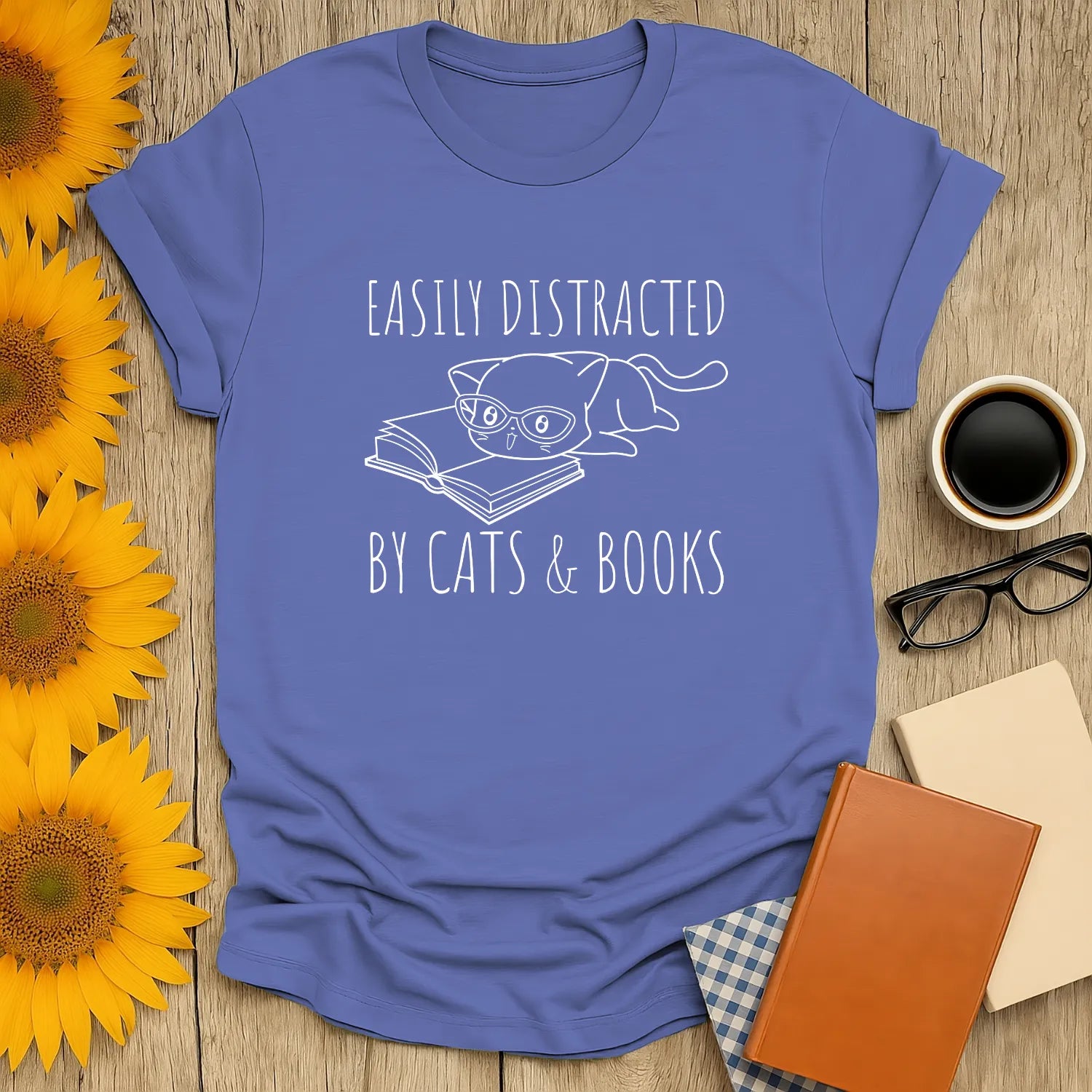 Light blue t-shirt with a cat in glasses and text: 'Easily Distracted by Cats & Books.' Perfect cozy book shirt for cat lovers.