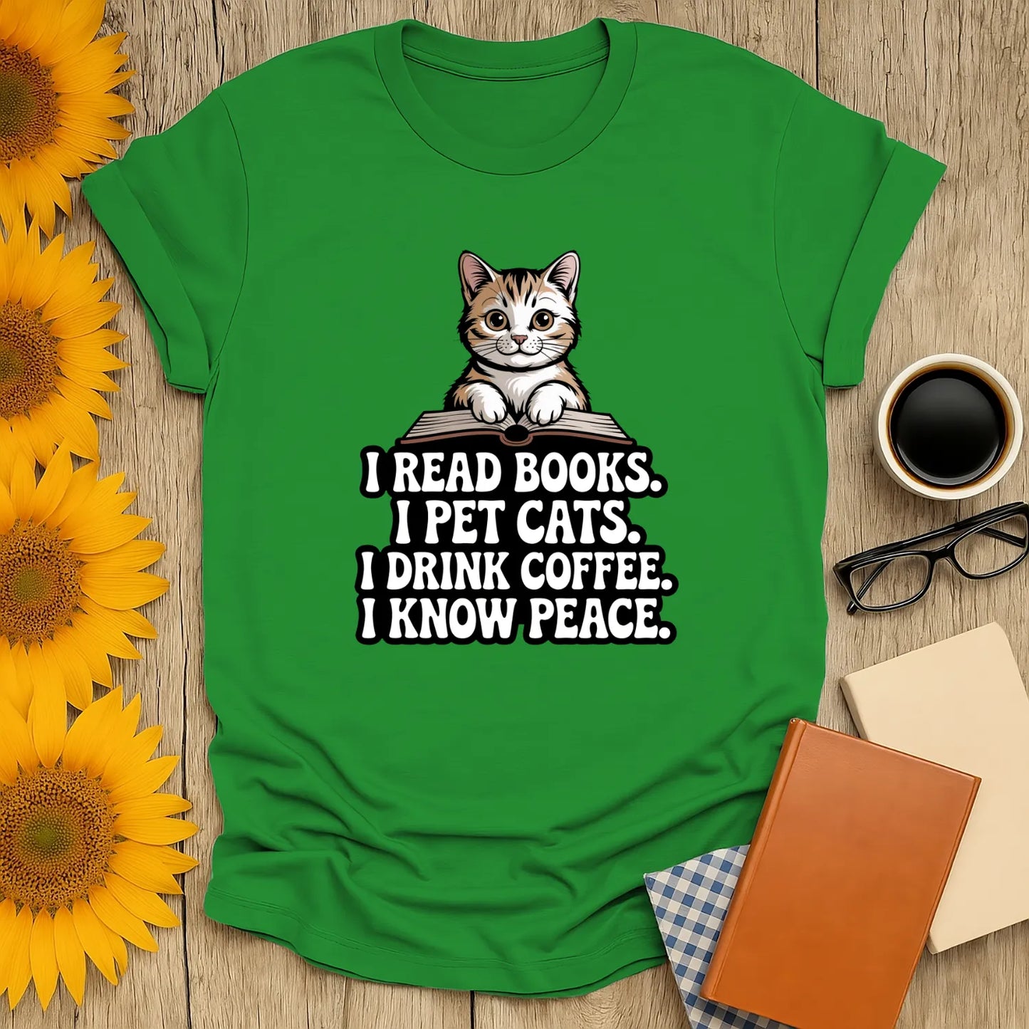 Green t-shirt featuring a cute cat illustration with text: 'I READ BOOKS. I PET CATS. I DRINK COFFEE. I KNOW PEACE.' Perfect for book lovers!