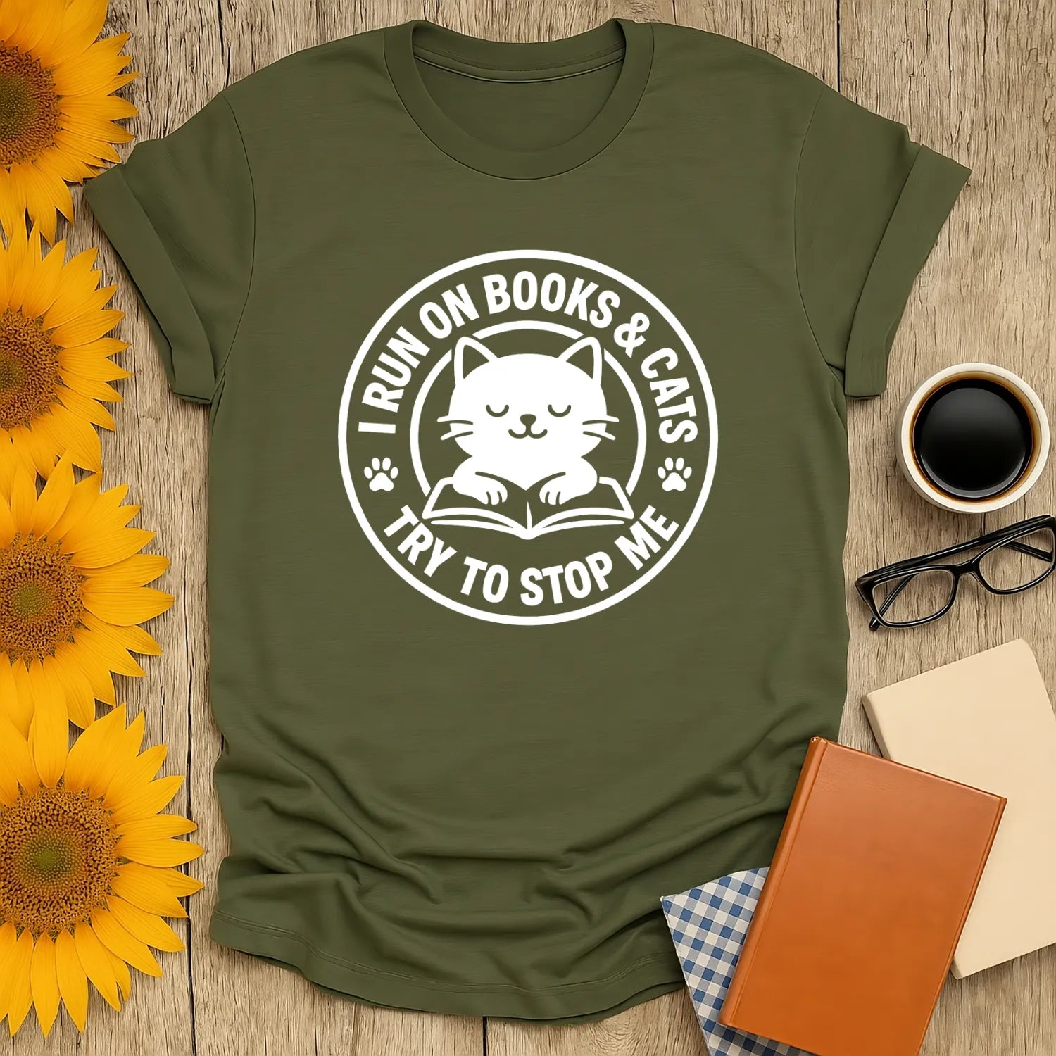 Cozy green t-shirt featuring a cute cat illustration and text: 'I RUN ON BOOKS & CATS TRY TO STOP ME'. Perfect gift for cat lovers!