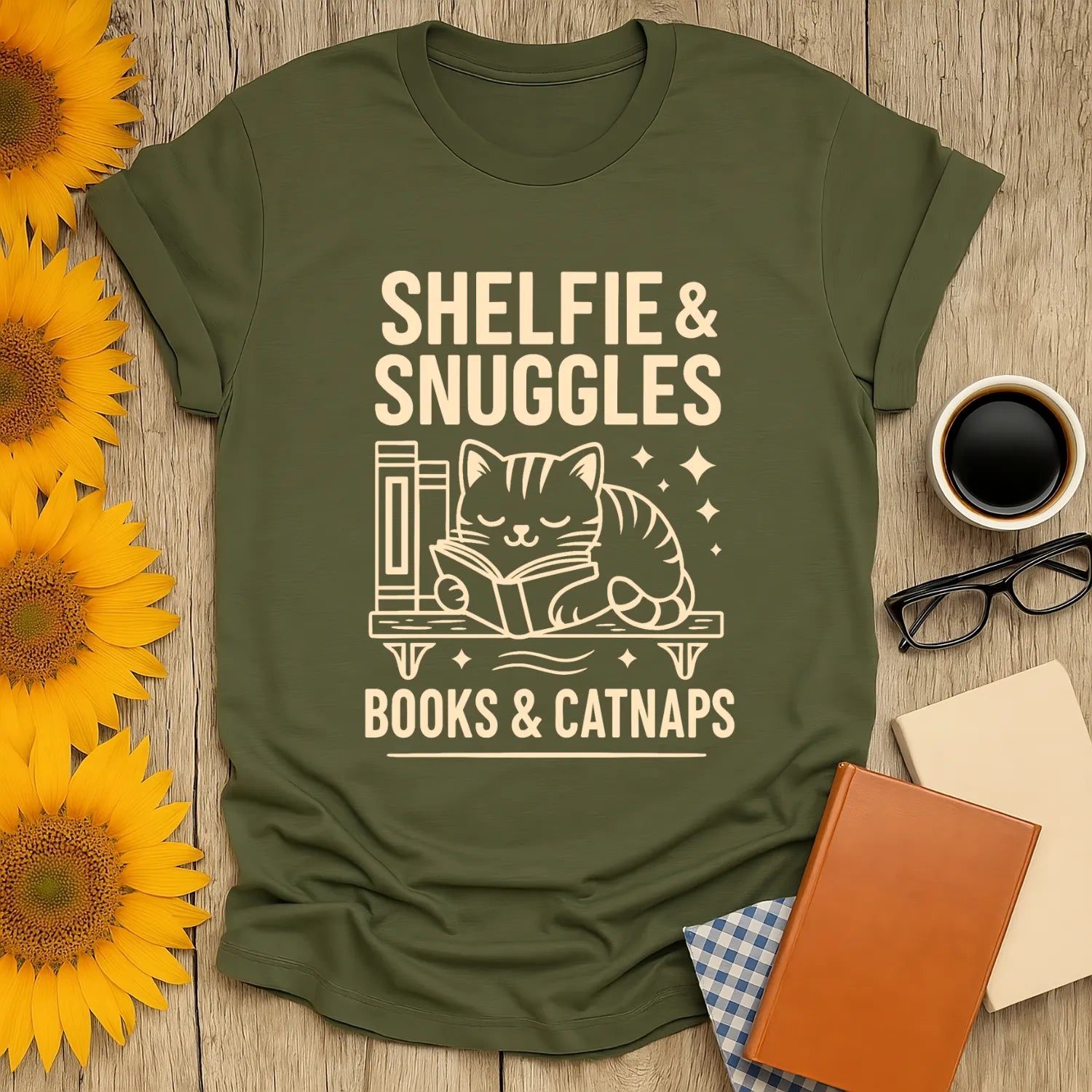 Warm olive tee featuring a sleeping cat reading, with 'Shelfie & Snuggles' text—perfect for book lovers and cat enthusiasts.