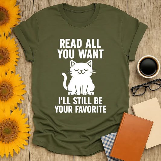Cozy olive t-shirt featuring a cute cat illustration and text: 'Read all you want, I’ll still be your favorite.' Perfect for book lovers!