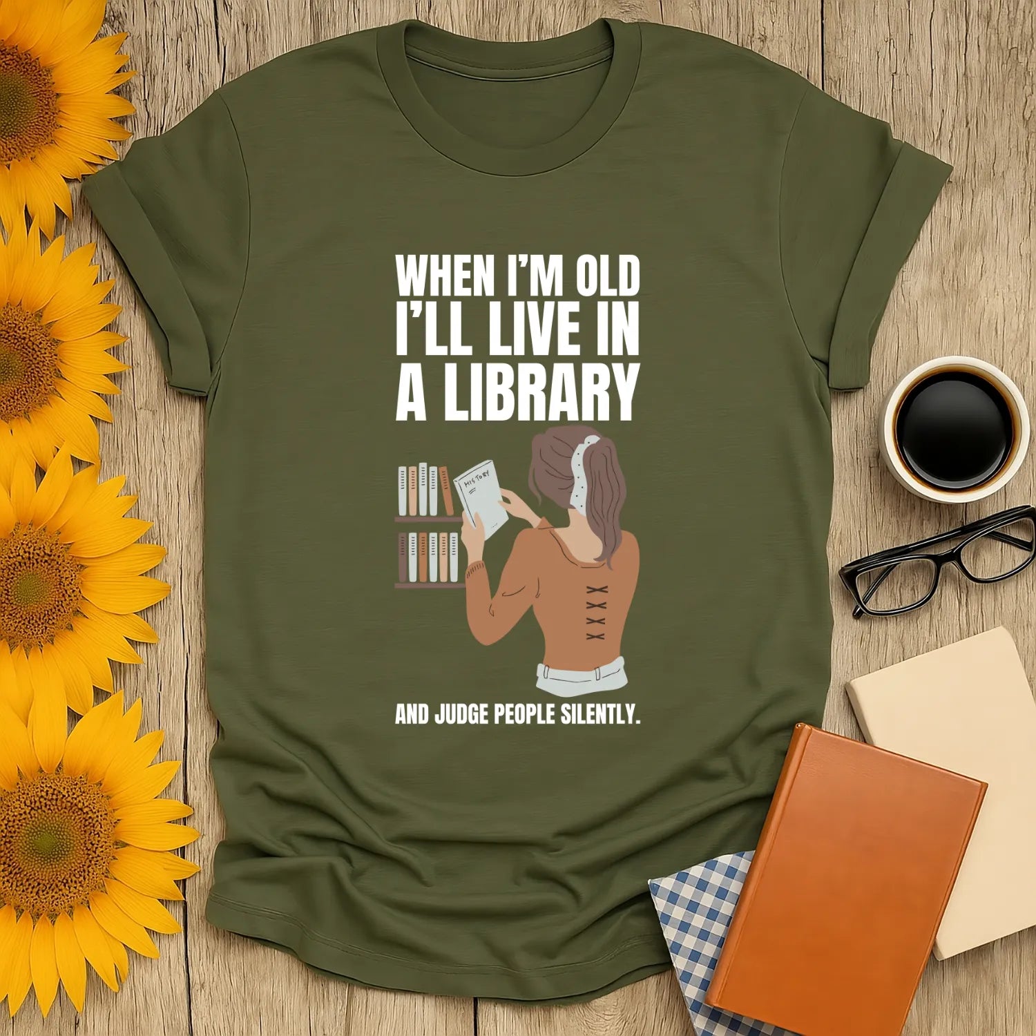 Funny reading tee with a woman in a library, text: 'When I'm old I'll live in a library and judge people silently.' Perfect gift for book lovers!