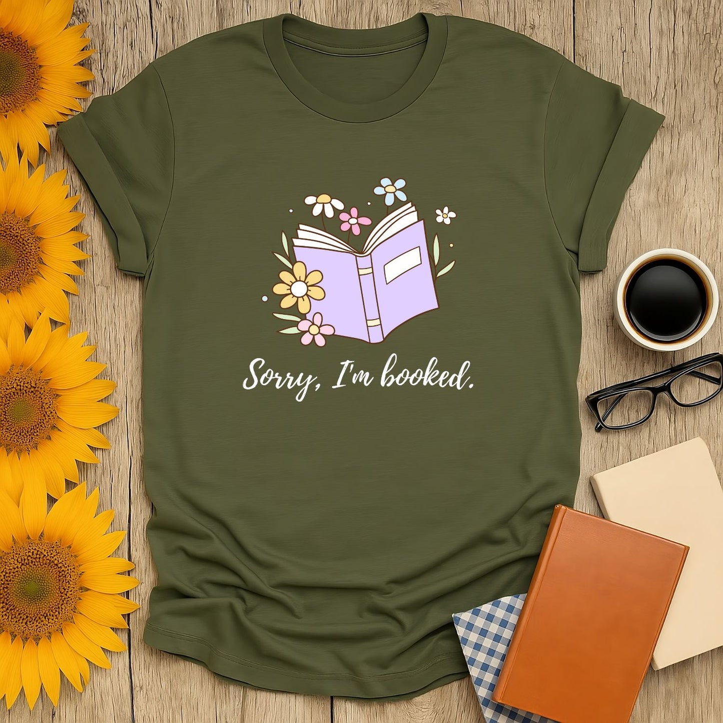 A cozy olive tee featuring an open book with flowers and the text 'Sorry, I'm booked.' Perfect for book lovers who savor cats, coffee, and tea!