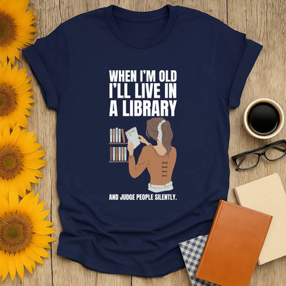 Funny book lover shirt featuring woman in a library with text 'I'll live in a library and judge people silently'