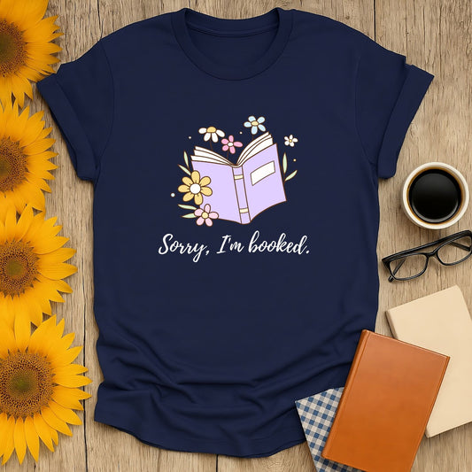 Cozy navy book lover shirt featuring an open book with flowers and the text 'Sorry, I'm booked.' Perfect gift for readers!