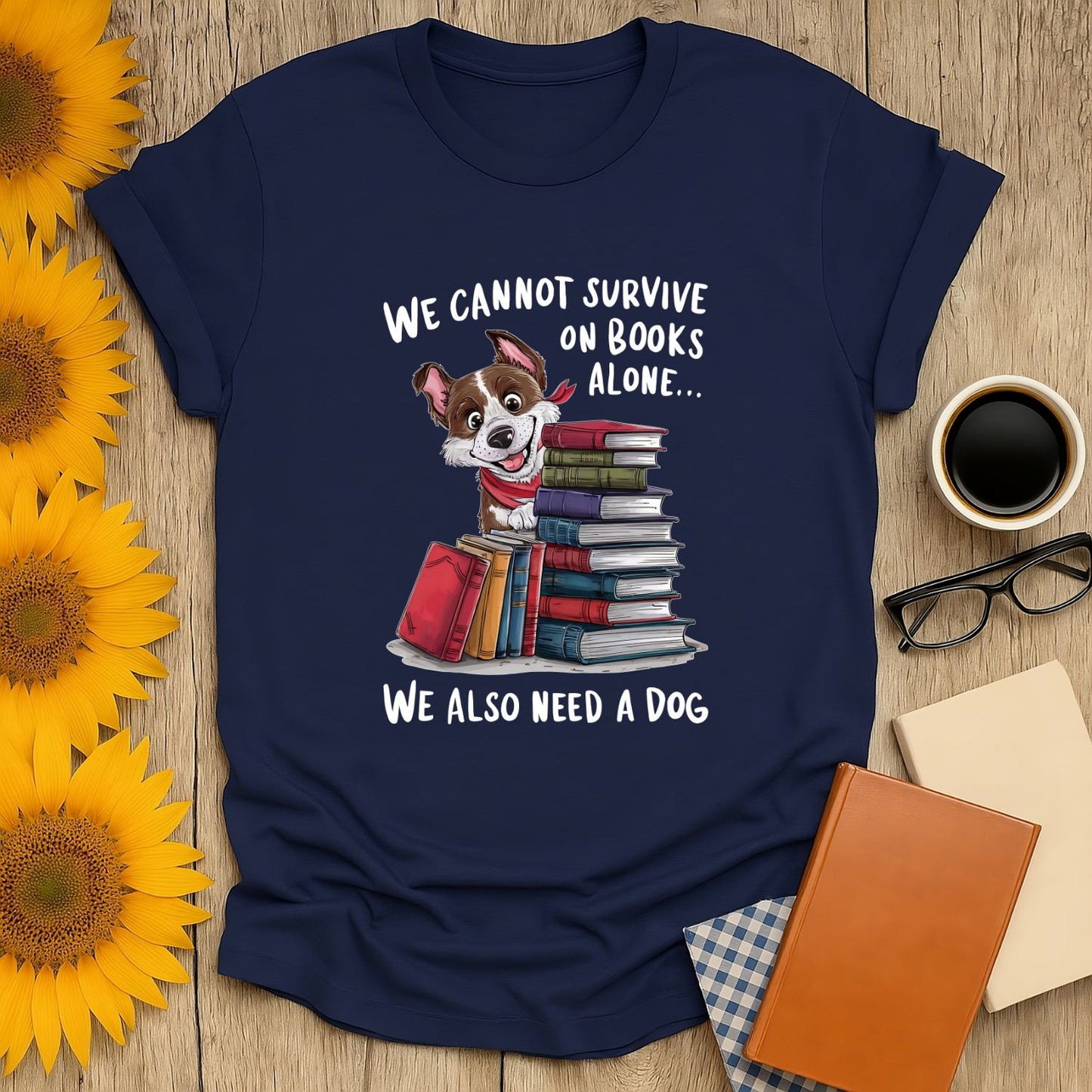 Navy shirt with 'We cannot survive on books alone...' text, featuring a dog and stacked books—perfect for cozy book lovers!