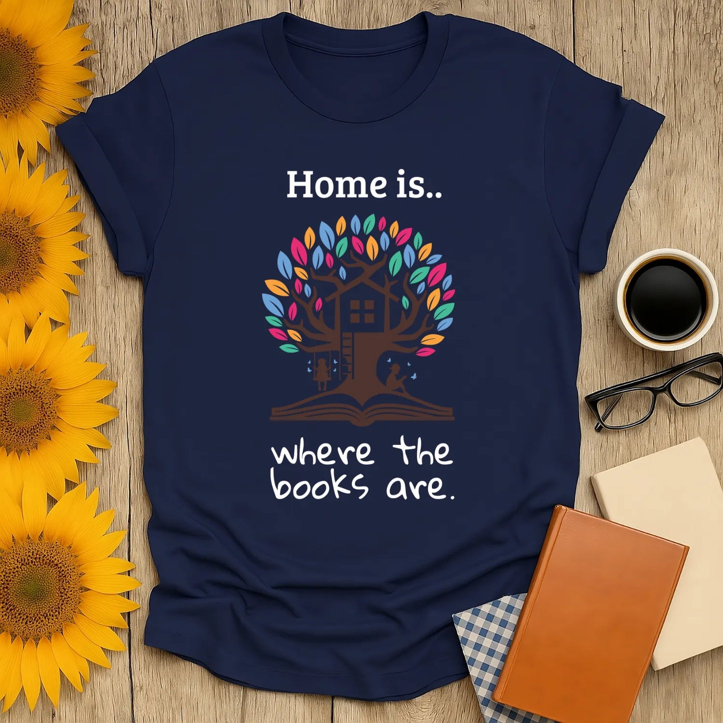Cozy book lover shirt featuring a whimsical tree with a house and the phrase 'Home is where the books are.' Perfect gift for readers!