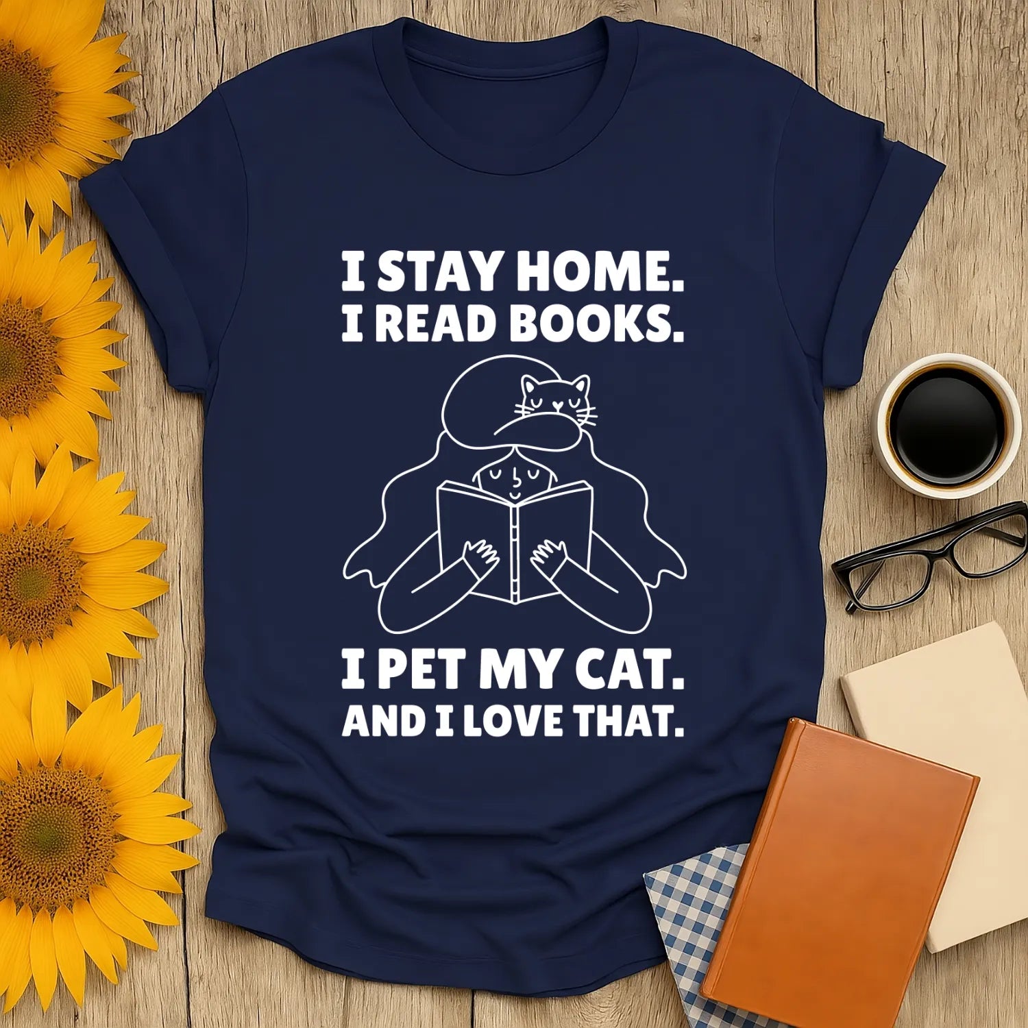 Unisex navy t-shirt featuring a whimsical design: a woman reading with a cat, captioned 'I stay home. I read books. I pet my cat. And I love that.'