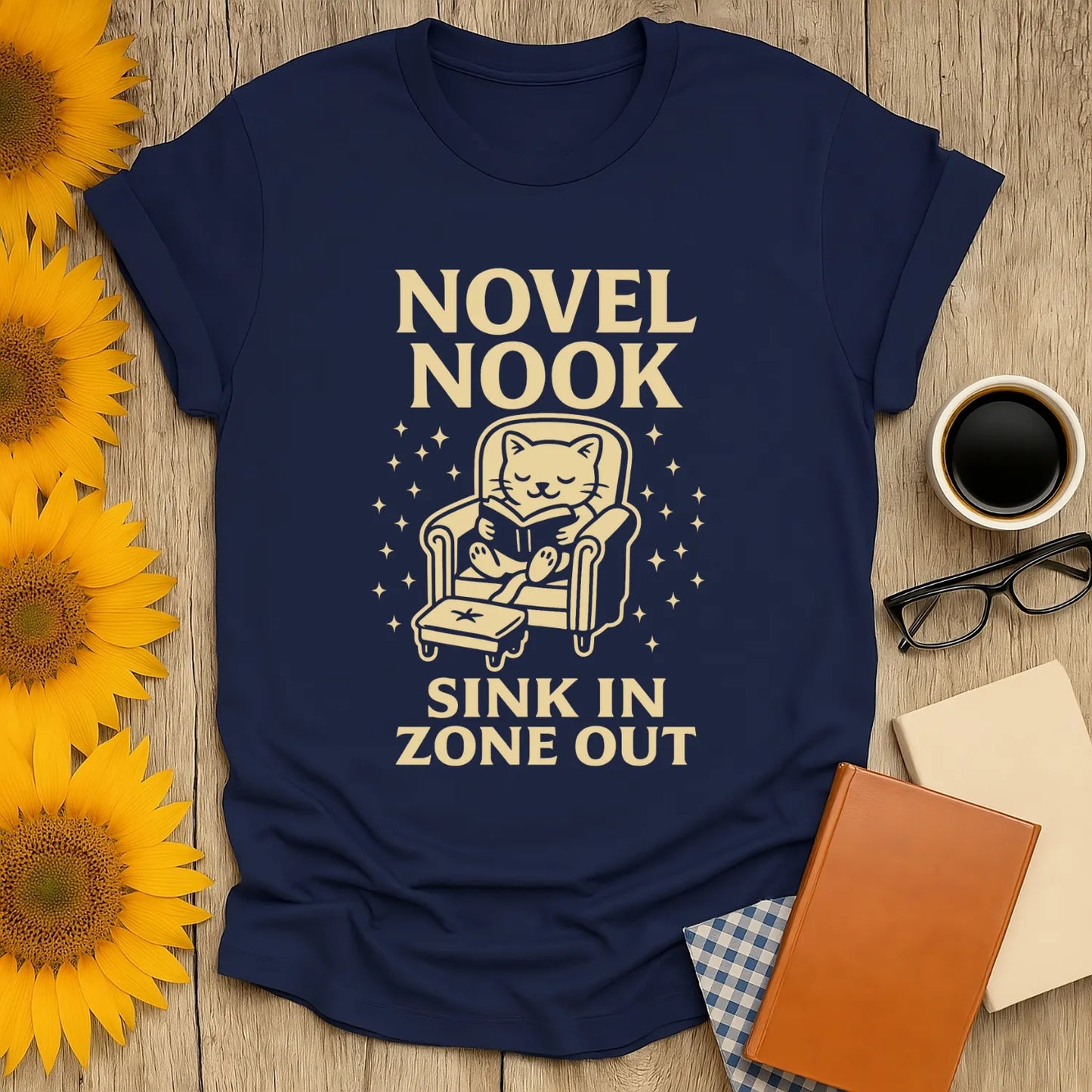 Cozy cat in armchair graphic on navy Novel Nook t-shirt, perfect for book lovers who enjoy cats, coffee, and humor.